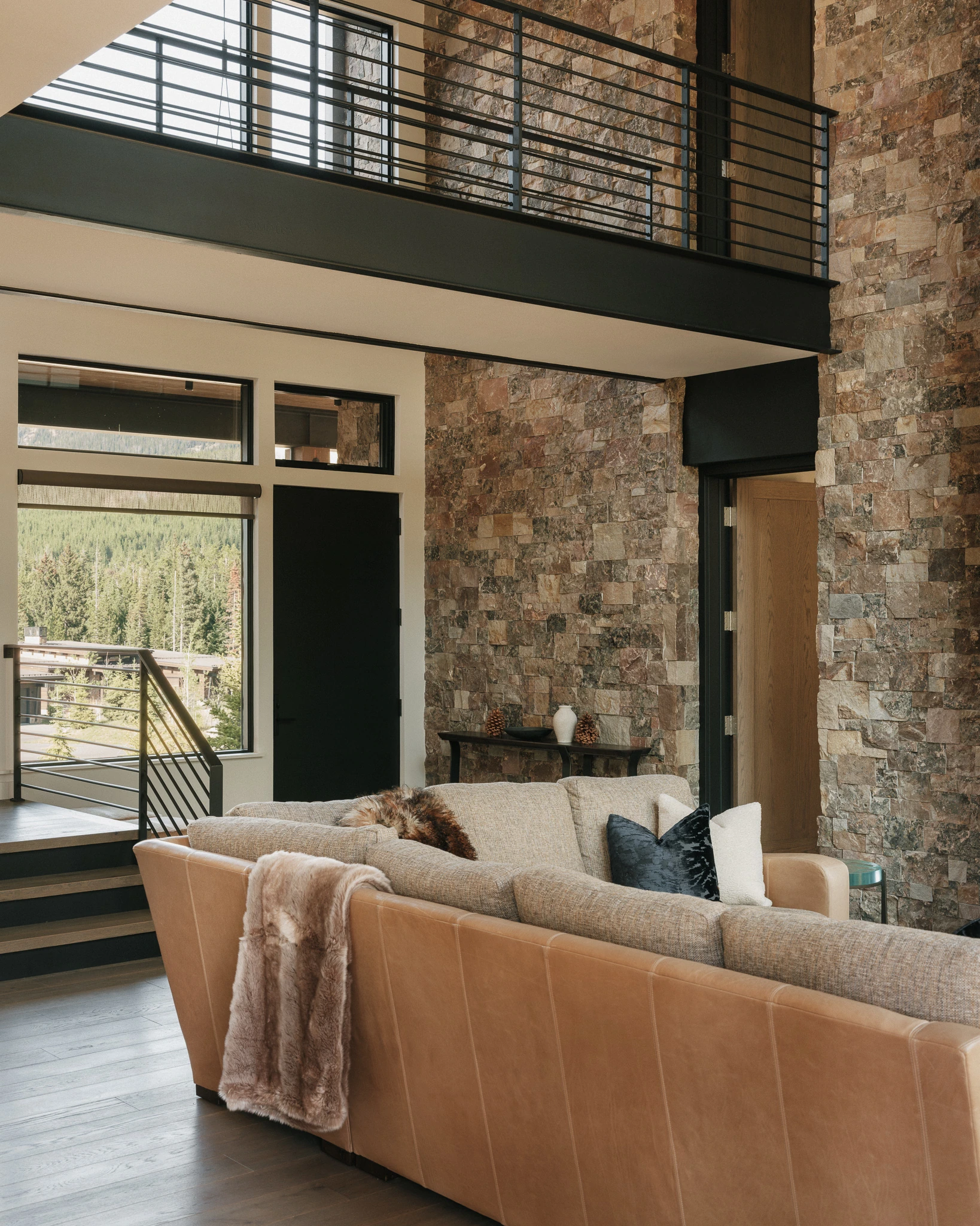Great room with catwalk above and stacked-stone fireplace wall — architectural photography Big Sky Montana, Reid Smith Architects